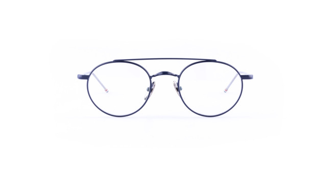 The Thom Browne 101 features round, black-rimmed eyeglasses with thin metal frames and clear lenses, displayed against a white background.