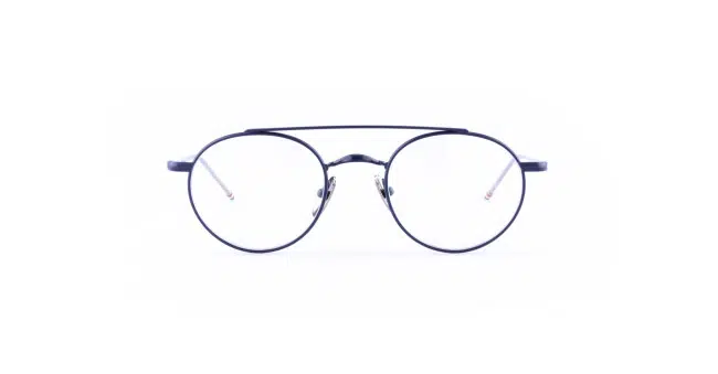 The Thom Browne 101 features round, black-rimmed eyeglasses with thin metal frames and clear lenses, displayed against a white background.