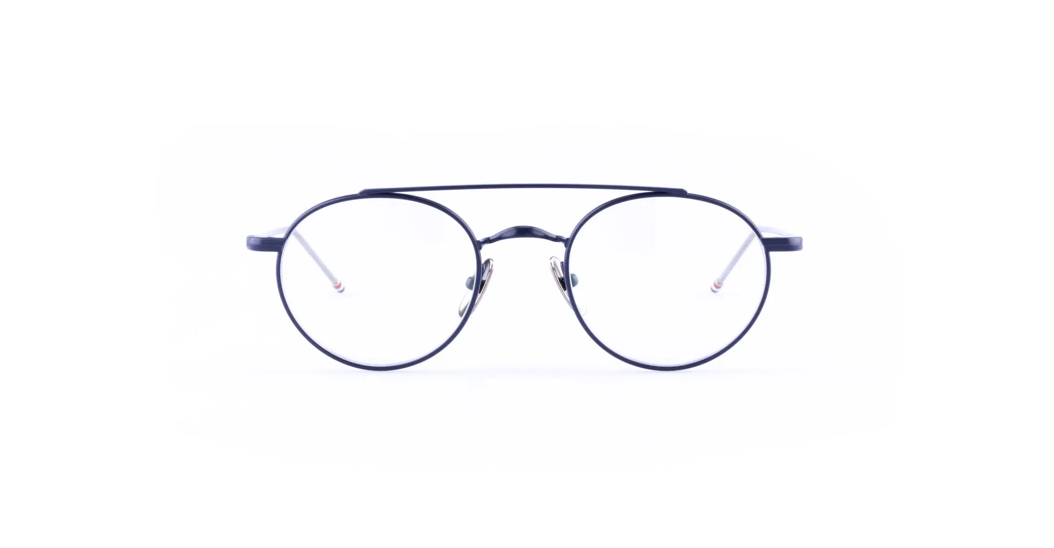 The Thom Browne 101 features round, black-rimmed eyeglasses with thin metal frames and clear lenses, displayed against a white background.