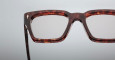 Close-up of the upper half of Jacques Marie Mage Ichikawa rectangular eyeglasses with a dark tortoiseshell frame set against a plain light gray background.
