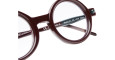 Close-up of round, dark red Kuboraum P1 eyeglass frames with clear lenses, showing detail of the bridge and temple arm with white product info text on a white background.