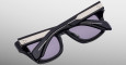 The Jacques Marie Mage Dealan 53 is shown from above with temples crossed and folded, featuring black frames, silver accents, and purple-tinted lenses on a light gray background.