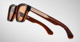 The Jacques Marie Mage Sonata is a pair of brown, rectangular sunglasses with thick frames and temples, metallic accents, and small round rivets near the hinges, displayed against a light gray background.