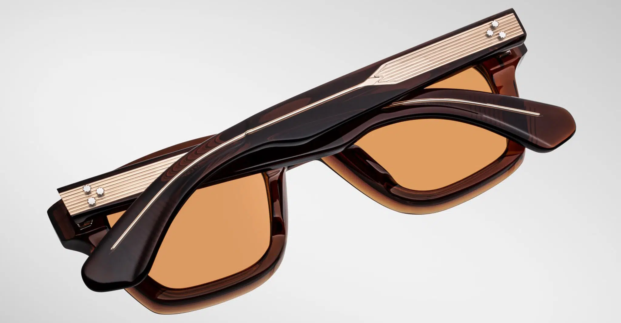 The Jacques Marie Mage Sonata sunglasses, featuring brown square frames and gold metal accents, are shown upside down with temples and top of the frames visible against a plain light background.