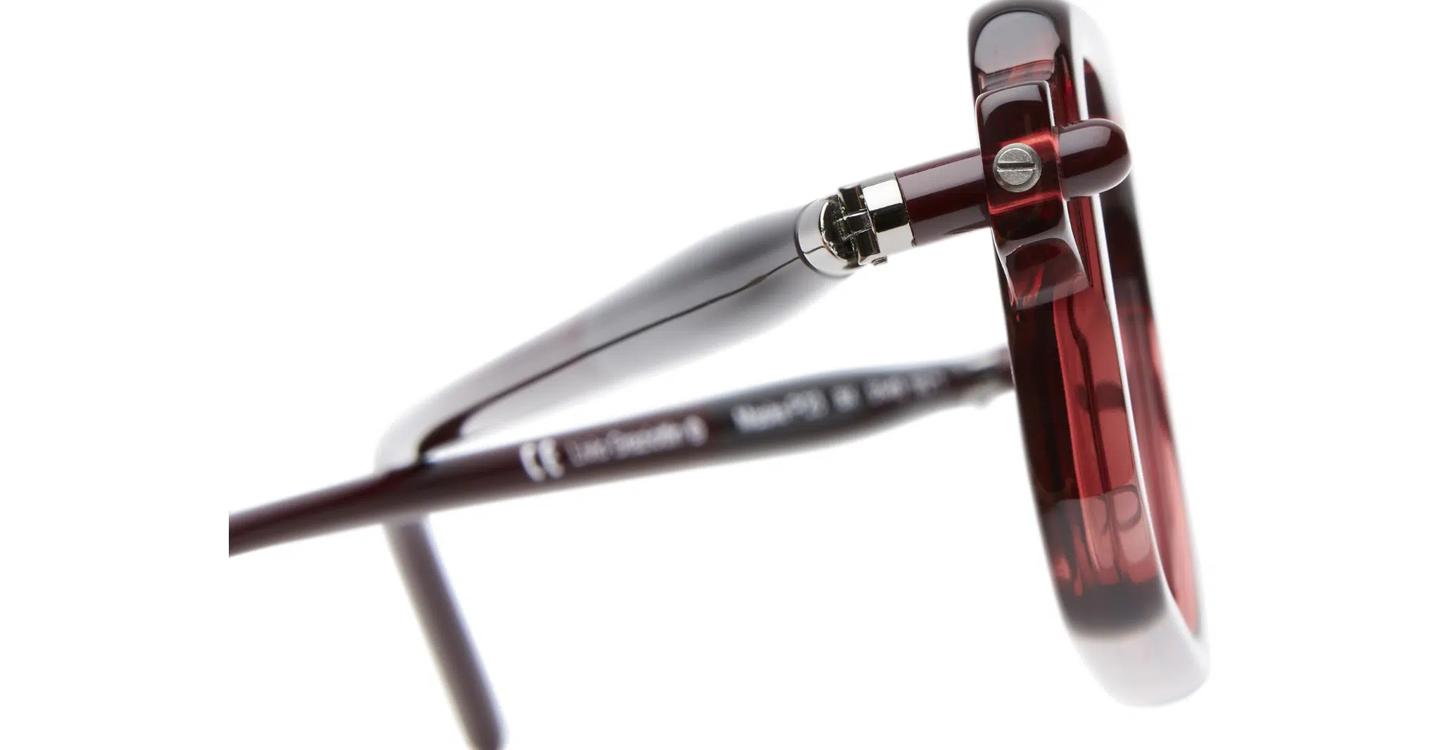 Close-up view of the hinge and arm of the Kuboraum P23 dark red eyeglasses, highlighting the glossy frame finish and detailed metal hinge mechanism.