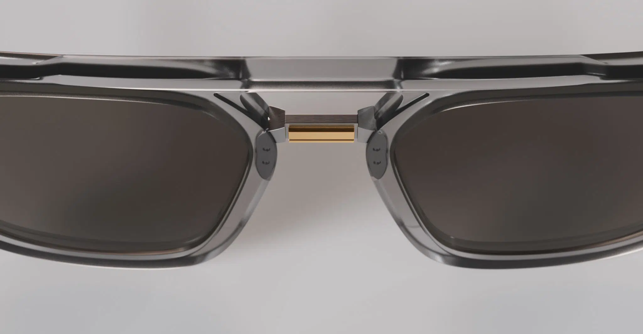 Close-up of Masunaga Master of Craft - 002: dark rectangular sunglasses featuring a metallic frame with a gold accent on the nose bridge, displayed against a light gray background.