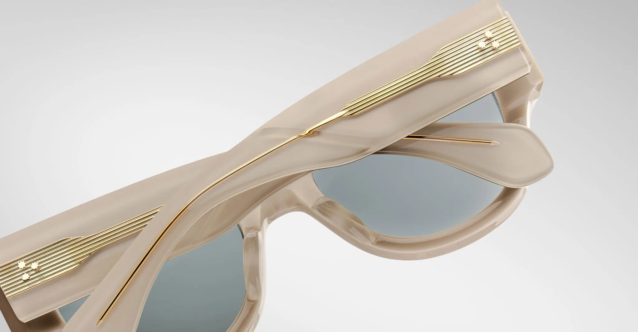 A close up view of the back of a pair of Jacques Marie Mage Chelsea beige, thick-framed sunglasses with dark lenses