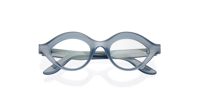 The Lapima Isa features oval-shaped eyeglasses with thick, translucent light blue frames, displayed against a white background. The folded temples are partially visible behind the lenses.