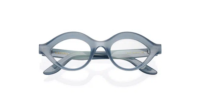 The Lapima Isa features oval-shaped eyeglasses with thick, translucent light blue frames, displayed against a white background. The folded temples are partially visible behind the lenses.