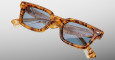 A pair of Jacques Marie Mage Casablanca rectangular tortoiseshell sunglasses with blue lenses is shown against a plain light gray background, with the arms folded.