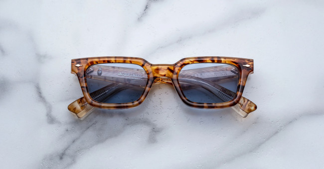 A pair of Jacques Marie Mage Casablanca rectangular tortoiseshell sunglasses with dark lenses laid flat on a white marble surface.