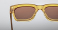 Close-up of Jacques Marie Mage Fellini rectangular sunglasses featuring translucent yellow frames and brown-tinted lenses set against a plain, light background.