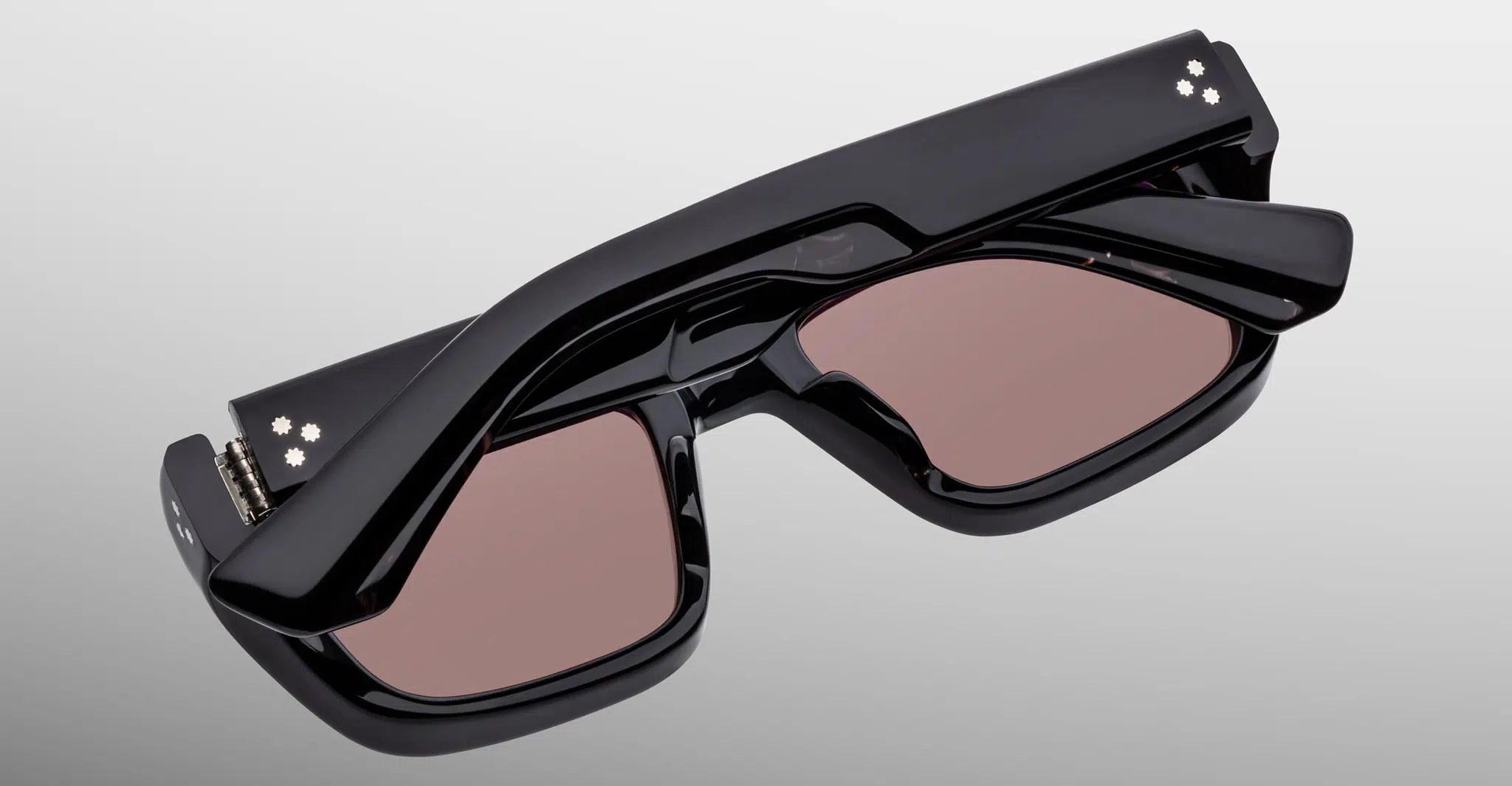 The Jacques Marie Mage Walker is a pair of black, futuristic smart glasses with rectangular tinted lenses and built-in electronics on the temples, displayed folded against a light gray background.
