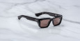 Jacques Marie Mage Walker black rectangular sunglasses with thick frames and dark tinted lenses rest on a white marble surface.