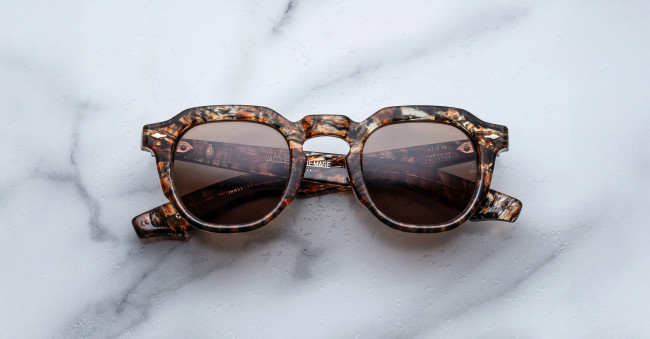 Jacques Marie Mage Firehole River: round tortoiseshell sunglasses with dark lenses, shown on a white marble surface.