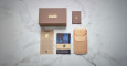 A Jacques Marie Mage Firehole River set—featuring a brown Yellowstone box, small brown booklet, tan leather pouch, card, and folded blue cloth with the Yellowstone bison logo—is displayed on white marble.