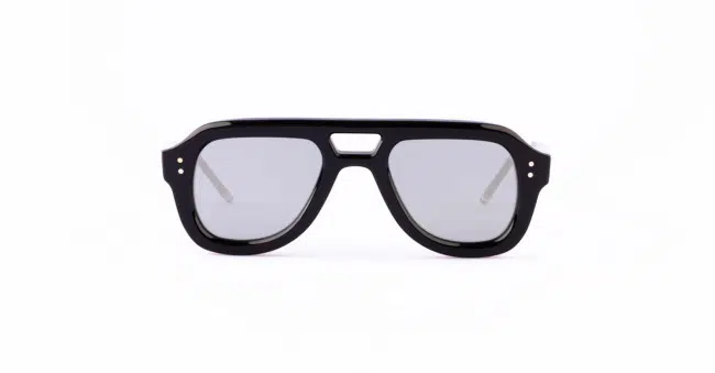Black, thick-rimmed Thom Browne sunglasses with gray lenses and a flat top design.