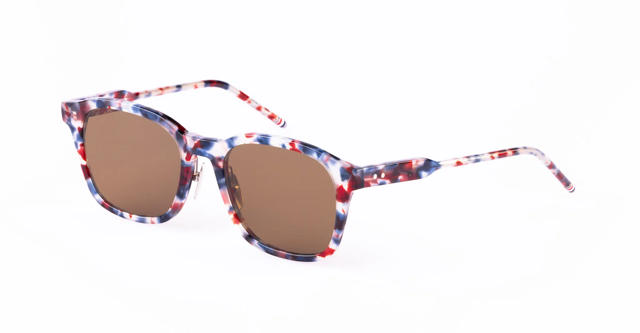 A pair of Thom Browne sunglasses with brown lenses and a multicolored, speckled frame in shades of red, white, and blue.