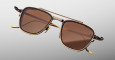The Jacques Marie Mage 1992 are stylish gold-framed sunglasses with large brown-tinted lenses, a double bridge, decorative gold accents, and yellow temple tips set against a light gray background.