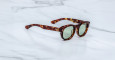 Jacques Marie Mage Dr. Dream tortoiseshell sunglasses with round green lenses displayed on a white marble surface.