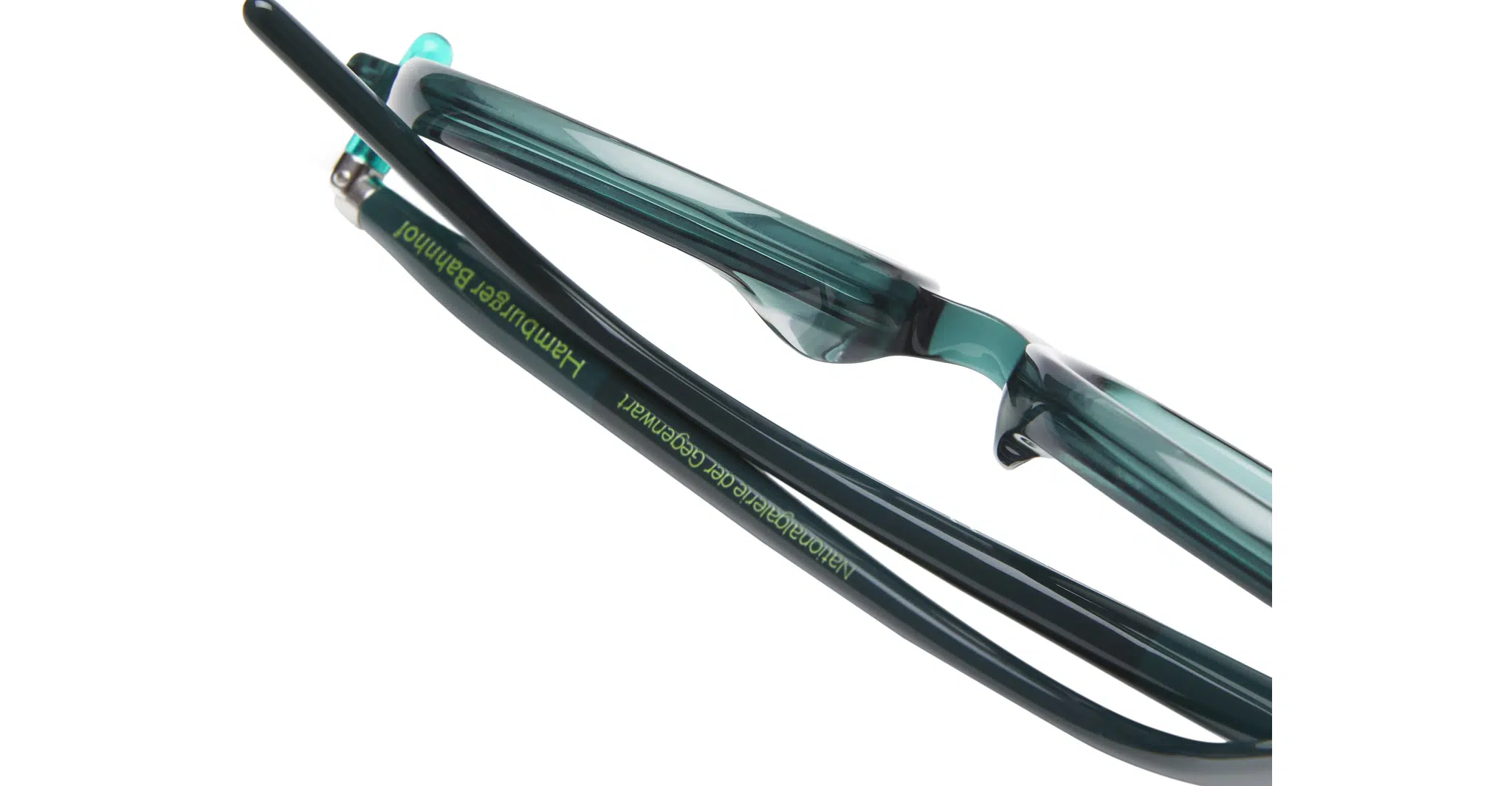 Close-up of teal and black eyeglasses with Nationalgalerie der Gegenwart Hamburger Bahnhof written in green text on the arm. The background is white.