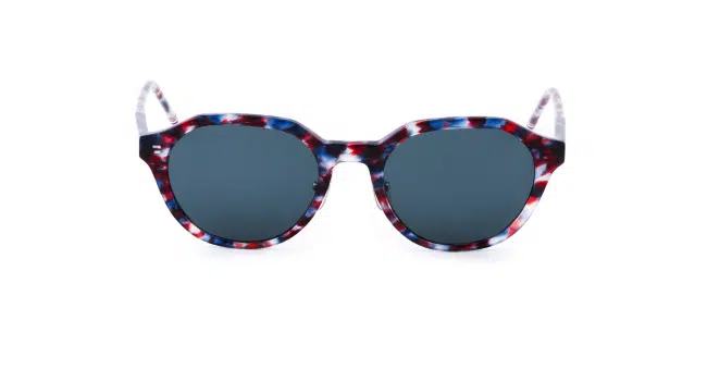 Sunglasses with round dark lenses and a thick, multicolored frame featuring a red, white, and blue tortoiseshell pattern.