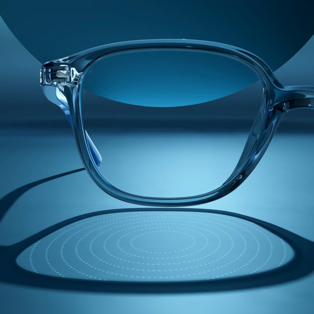 Concept image representing Stellest lenses, showing a clear eyeglass frame over a blue surface with a circular dot pattern beneath the lens.