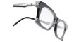 Close-up of Kuboraum D75 black square eyeglasses with clear lenses, silver metal hinge, and decorative temple detail, shown at an angle on a white background.