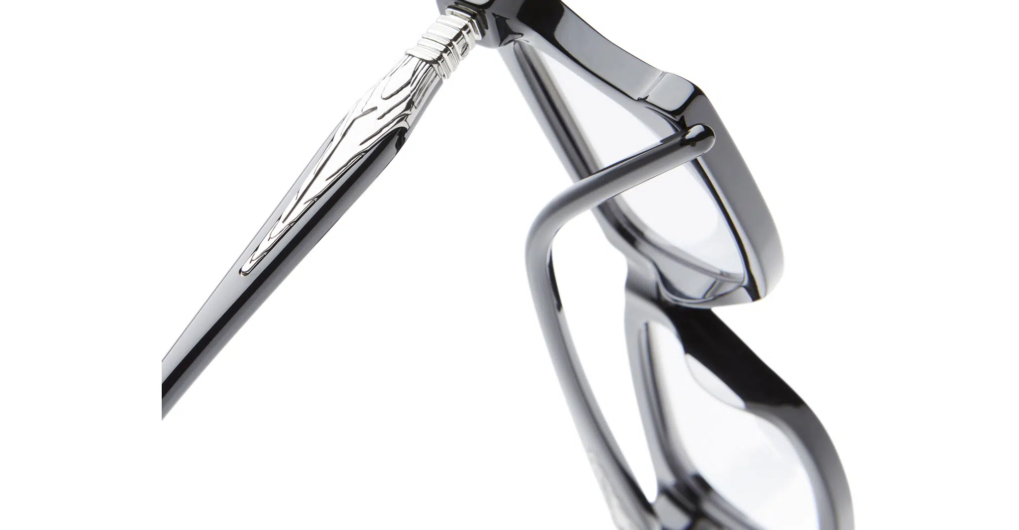 Close-up of Kuboraum D75 black eyeglasses with clear lenses, highlighting the hinge area and silver decorative detail on the temple against a white background.