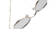 Close-up of the Kuboraum H11 oval sunglasses featuring gold metal frames and grey lenses, partially shown against a white background.