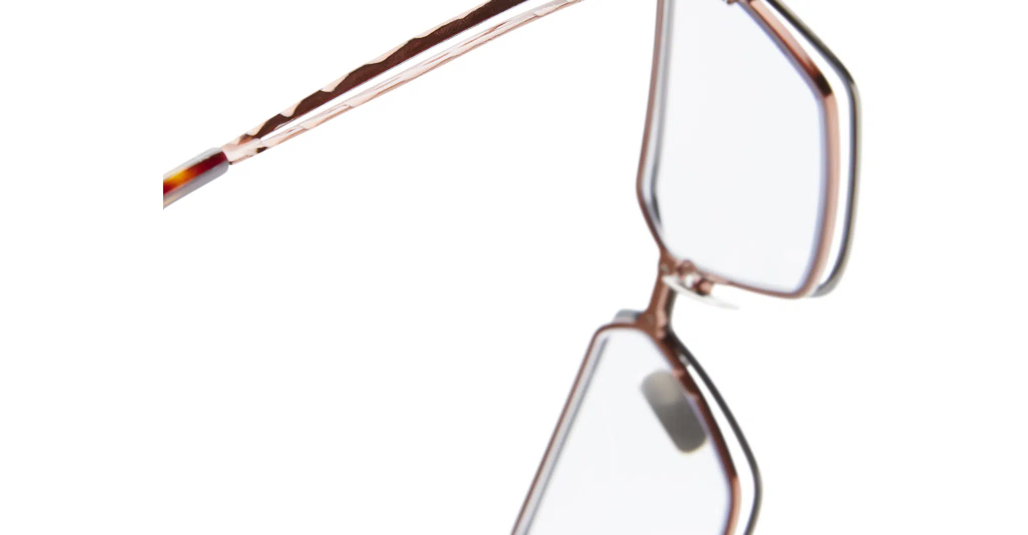 Kuboraum-H15-BZ-Gun-Metal-Optical-KROH15BZ000000OP-Detail2-Dan-Deutsch Close-up of the Kuboraum H15 eyeglasses featuring rose gold frames and clear lenses, displayed at an angle on a white background.