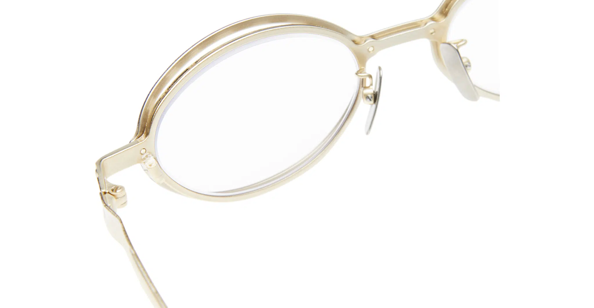 Kuboraum-H18-GD-Gold-Optical-KROH18GD000000OP-Detail4-Dan-Deutsch Close-up of Kuboraum H18 gold-rimmed round eyeglasses with clear lenses, highlighting the frame, nose pads, and left temple against a white background.