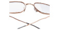 Close-up view of Kuboraum H22 eyeglasses in rose gold metal with clear lenses, adjustable nose pads, and partially visible temple arms crossed at the bottom against a white background.