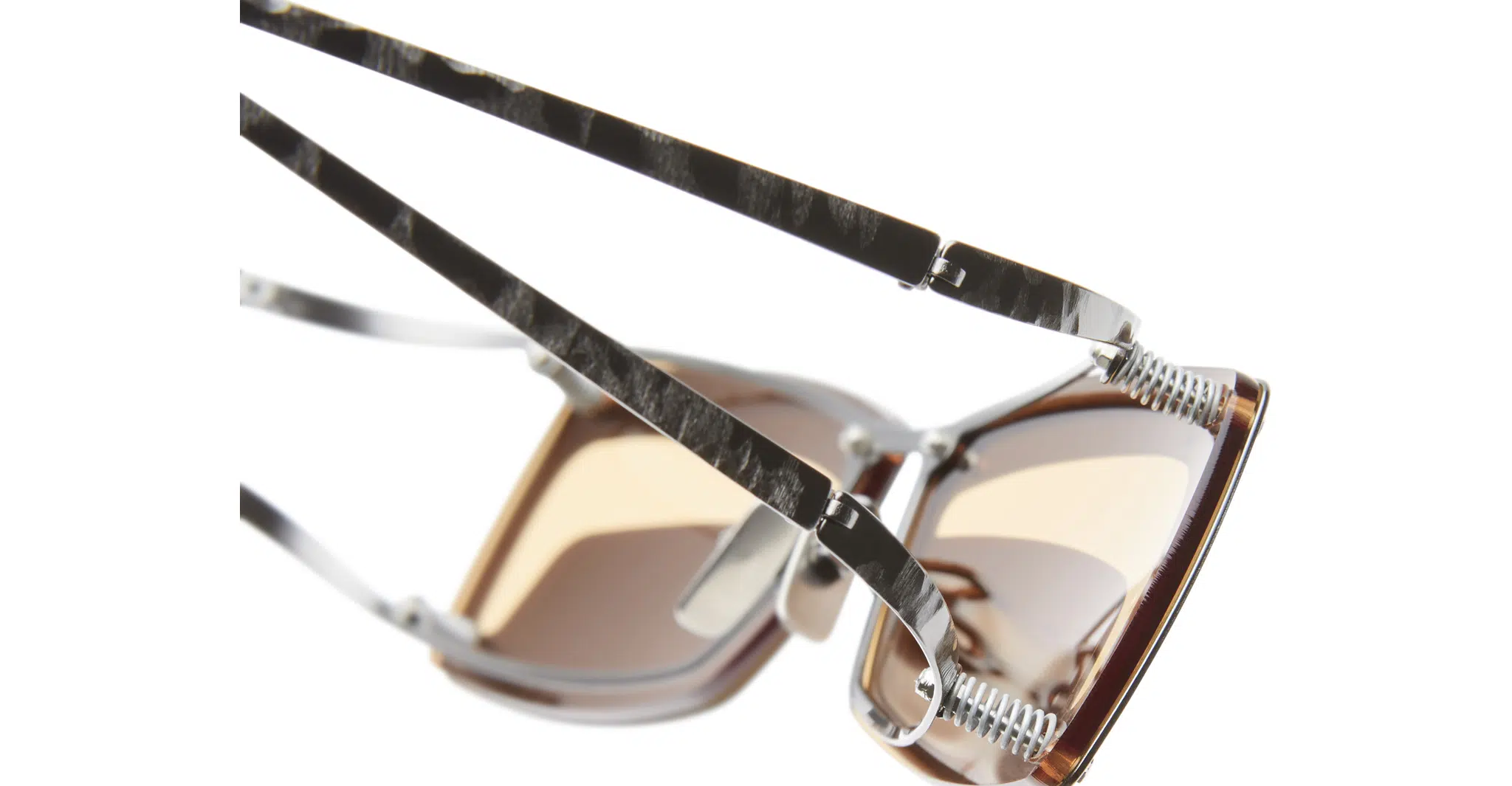 Kuboraum-I50 RH_DARK GUN METAL 09-Dan-Deutsch Close-up of Kuboraum I50 sunglasses with brown-tinted lenses and metal frames, featuring textured, marble-like patterned arms, set against a white background.