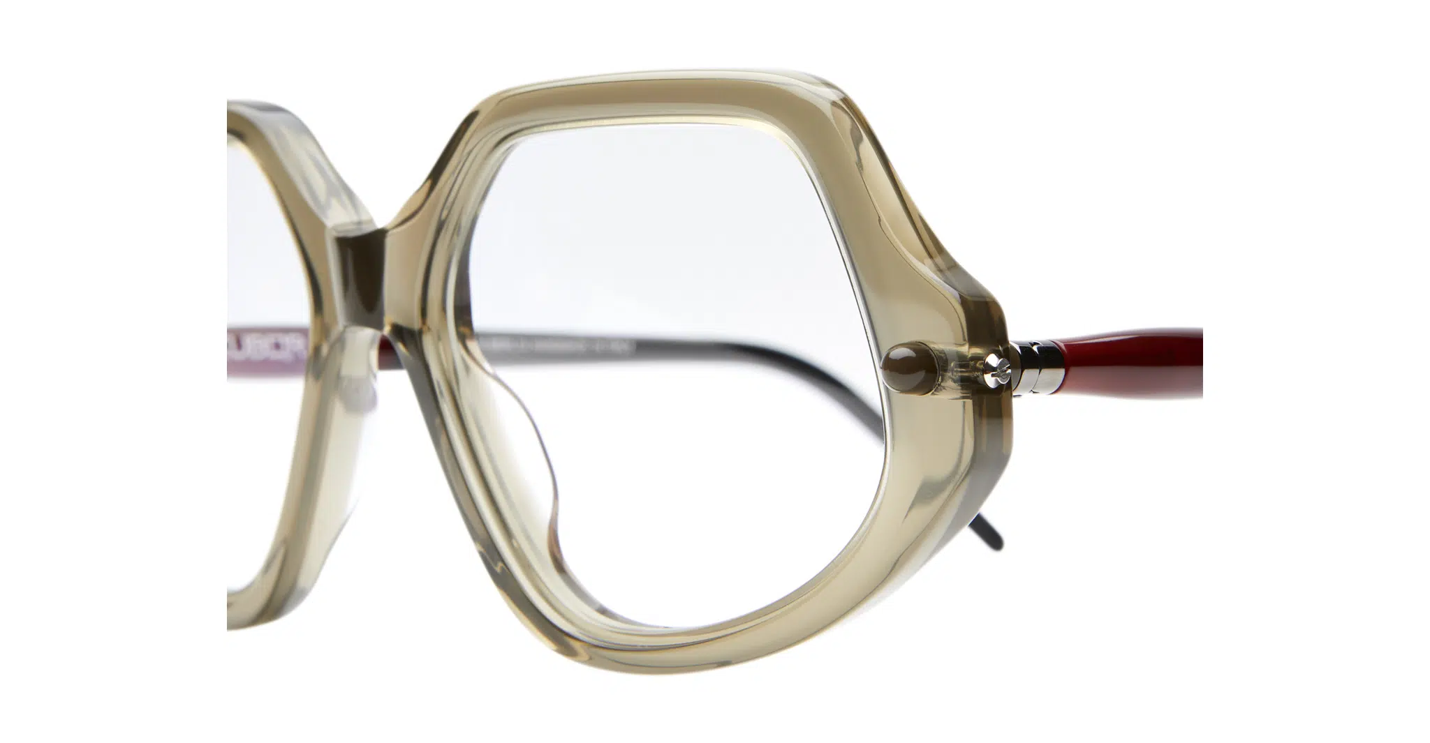 Kuboraum-P20-OL-Olive-KROP20OL000000OP-Detail4-Dan-Deutsch Close-up of Kuboraum P20 oversized eyeglass frames featuring geometric design, transparent beige rims, and red temples against a white background.