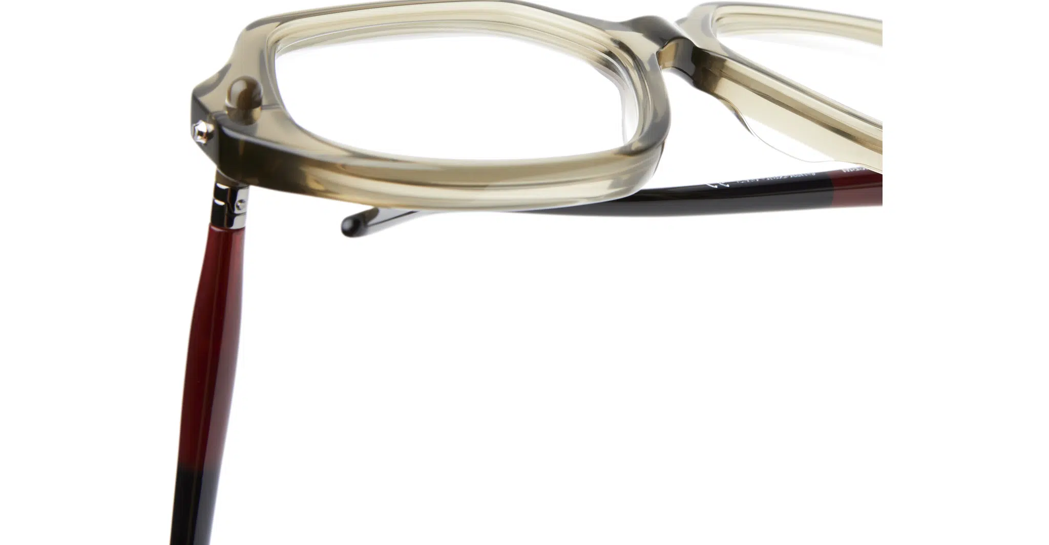 Kuboraum-P20-OL-Olive-KROP20OL000000OP-Detail5-Dan-Deutsch Close-up of Kuboraum P20 beige square eyeglass frames with thick rims, highlighting the corner hinge and one red and black temple arm extending outward.