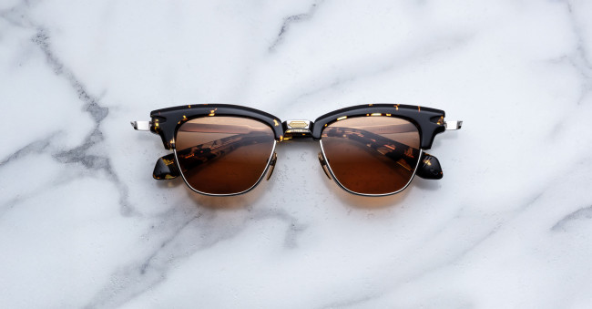 The Jacques Marie Mage Sartre tortoiseshell sunglasses with brown lenses rest on a white marble surface.