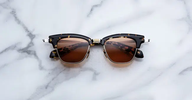 The Jacques Marie Mage Sartre tortoiseshell sunglasses with brown lenses rest on a white marble surface.