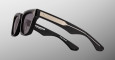 Jacques Marie Mage Torrance sunglasses, featuring dark lenses, gold-accented arms, and white branding on the inner temple, are shown against a gradient gray background.